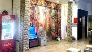 A modern interior with a stone accent wall, a television, a refrigerator, and a Coca-Cola vending machine. - An Chi Hotel SG - by BAY LUXURY (Ho Chi Minh City)
