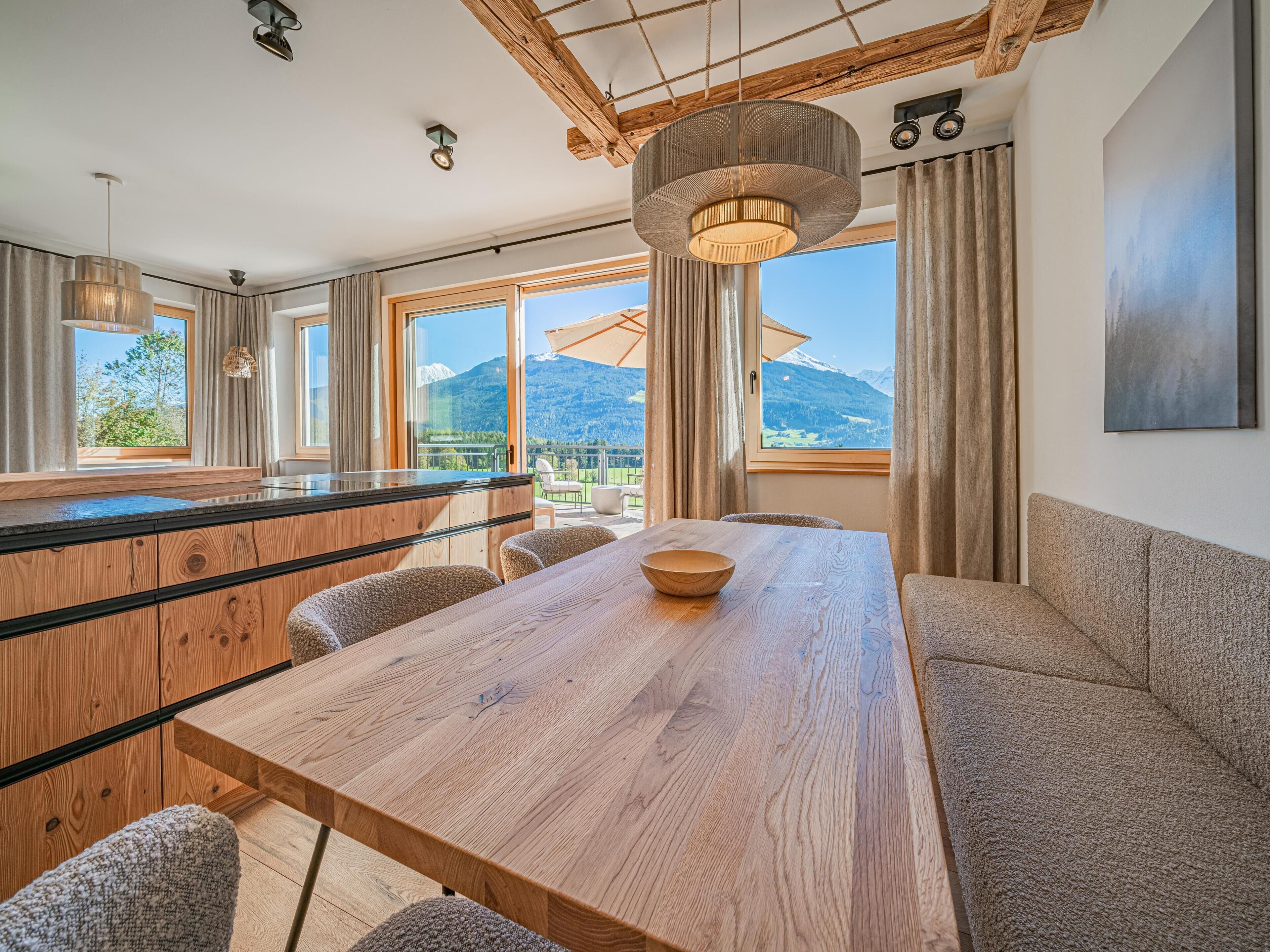 Une cuisine moderne avec des meubles en bois, un grand îlot central et une vue sur les montagnes.