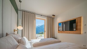 Een hotelkamer met een bed, een raam met gordijnen, een spiegel aan de muur en uitzicht op bergen.