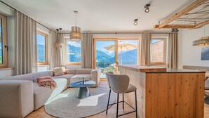 Een moderne woonkamer met een bank, een ronde salontafel en een barretje.