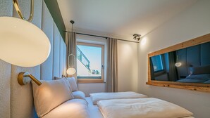 Quarto com cama, janela com vista para uma escada e luminária fixada na parede.