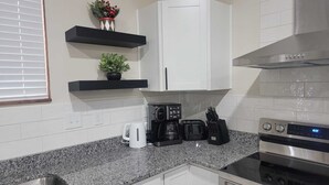 Een moderne keuken met witte kastjes, granieten aanrecht, een roestvrijstalen oven en een koffiezetapparaat.