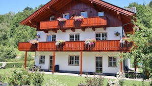 A two-story wooden building with balconies, large windows, and flower boxes.