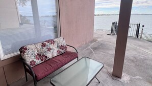 Ein Balkon mit einer Couch und einem Tisch, mit Blick auf ein Gewässer.
