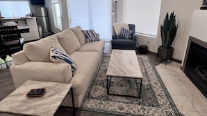 Ein modernes Wohnzimmer mit einem beigen Sofa, einem Couchtisch und einem Kamin.