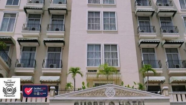 Un hotel de varios pisos con balcones, un elemento decorativo central y un letrero para un bar en la azotea.