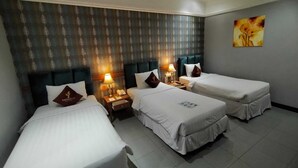 Una habitación de hotel con tres camas individuales, un papel tapiz estampado, un cuadro en la pared y una mesita de noche con lámpara.