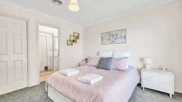 Un dormitorio con cama, mesitas de noche, espejo y lámpara de techo.