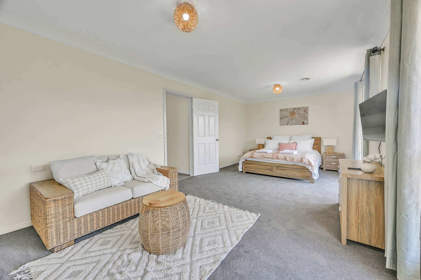 Een slaapkamer met een bed, een bank, een klein tafeltje en een decoratieve mand.