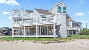 A two-story beachfront house with a balcony, large windows, and a covered porch area. - Cala Tortuga Beachfront Elevator, Hot Tub, Great Views (Galveston)