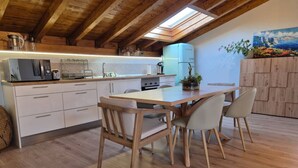 Een moderne keuken met houten balken, een eettafel met stoelen en een koelkast.