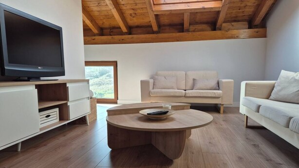 A modern living room with a TV, two sofas, a round coffee table, and wooden flooring. - C26A01 Apto Moderno en Tagle (Tagle)