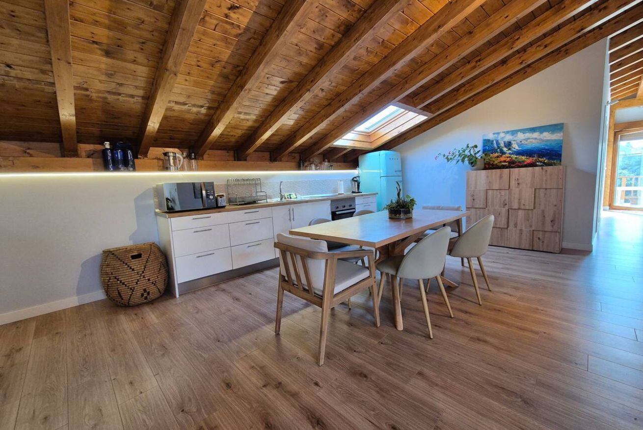 Una cucina con travi in legno, un tavolo da pranzo con sedie e un quadro appeso al muro.