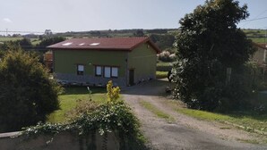 A single-story building with a red-tiled roof, a small porch, and a gravel driveway. - C26A01 Apto Moderno en Tagle (Tagle)