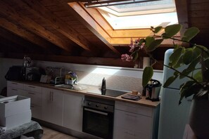 A kitchen with a skylight, wooden ceiling beams, a sink, a stove, and a refrigerator. - C26A01 Apto Moderno en Tagle (Tagle)