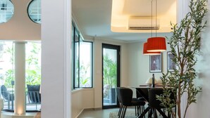 Een modern interieur met een trap die naar een eetgedeelte leidt, een potplant en een rode hanglamp.