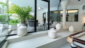 Een moderne hotellobby met grote ramen, kamerplanten en een zithoek met witte meubels.