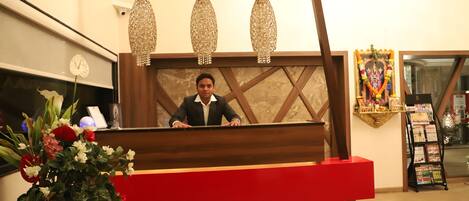 A reception desk with a wooden frame, a red counter, and a chandelier.