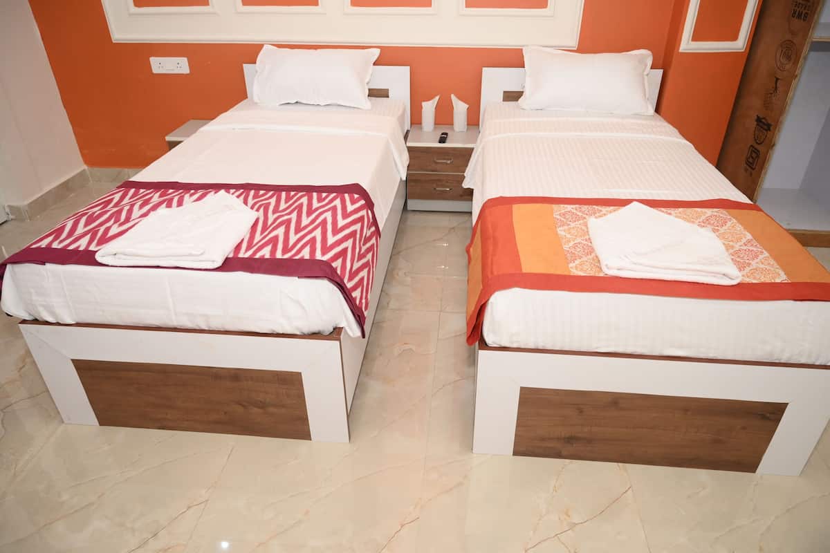 A hotel room with two beds, each with a wooden headboard, white bedding, and a patterned throw blanket.