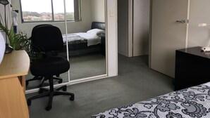 A bedroom with a bed, a desk, a chair, and a large window. - Sydney City Extra Large furnished Apartment  (Haymarket)