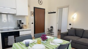 Un coin repas avec une table dressée pour quatre personnes, une machine à café et un canapé en arrière-plan.