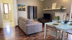 Ein modernes Wohnzimmer mit einer Couch, einem Fernseher und einem Esstisch.