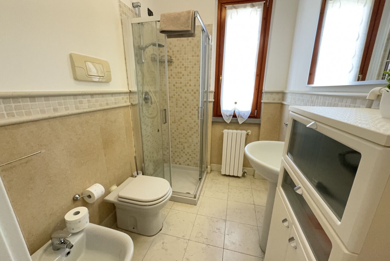 Une salle de bain équipée d’une douche, de toilettes, d’un lavabo et d’un grand miroir.