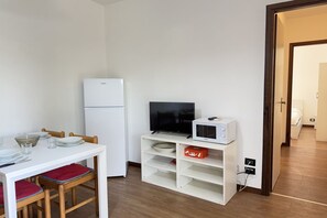 A compact living space with a kitchenette, a dining area, and a television. - 5' from Punta Gro Beach with Free Swimming Pool (Sirmione)