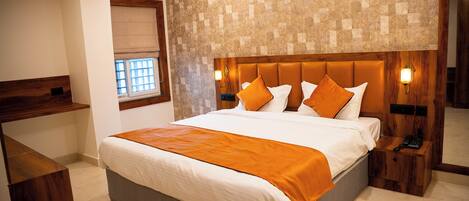 A modern hotel room with a large bed, wooden headboard, and a small bedside table with a phone.
