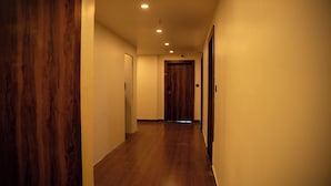 A hallway with wooden flooring and white walls, leading to a door at the end. - Hotel Orange (Bhubaneshwar)