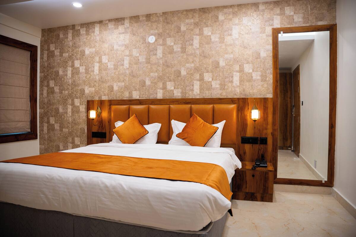 A hotel room with a large bed, wooden headboard, and a patterned wall.