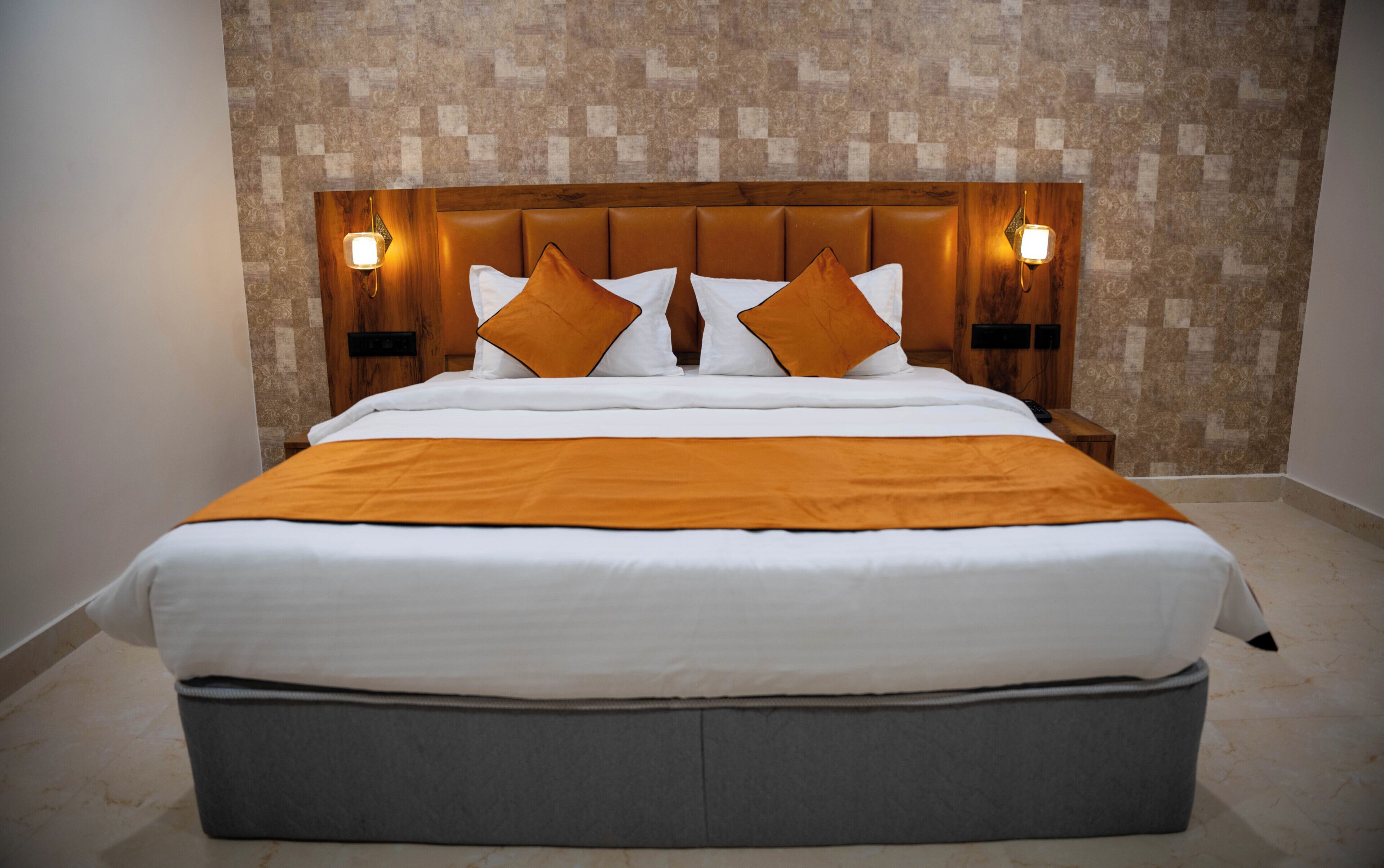 A large bed with a wooden headboard, two bedside tables, and a patterned wall.