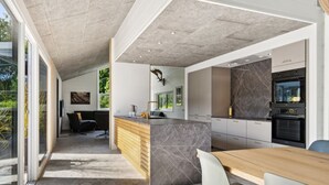 Una cocina moderna con una isla de mármol, horno empotrado y comedor con mesa y sillas de madera.
