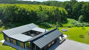 Una casa moderna con un amplio patio, piscina y césped bien cuidado.