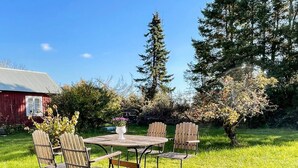 An outdoor seating area with a wooden table and chairs, surrounded by grass and trees. - 7 Person Holiday Home in Lottorp (Löttorp)