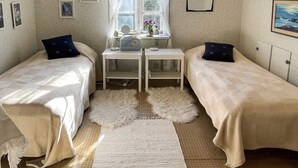 A cozy room with two beds, a small table with a radio, a window with curtains, and framed pictures on the walls. - 7 Person Holiday Home in Lottorp (Löttorp)