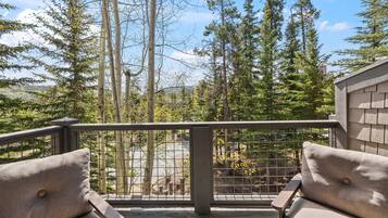 A balcony with a view of tall trees and a distant mountain range.
