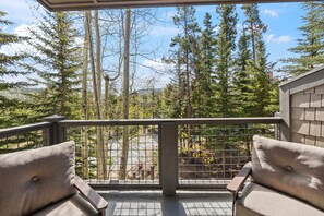 A balcony with a view of tall trees and a distant mountain range. - Mountain Thunder Lodge 2BR — gondola & Main St (Breckenridge)