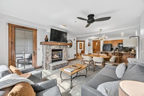A modern living room with a fireplace, a dining area, and a kitchen with wooden cabinets.