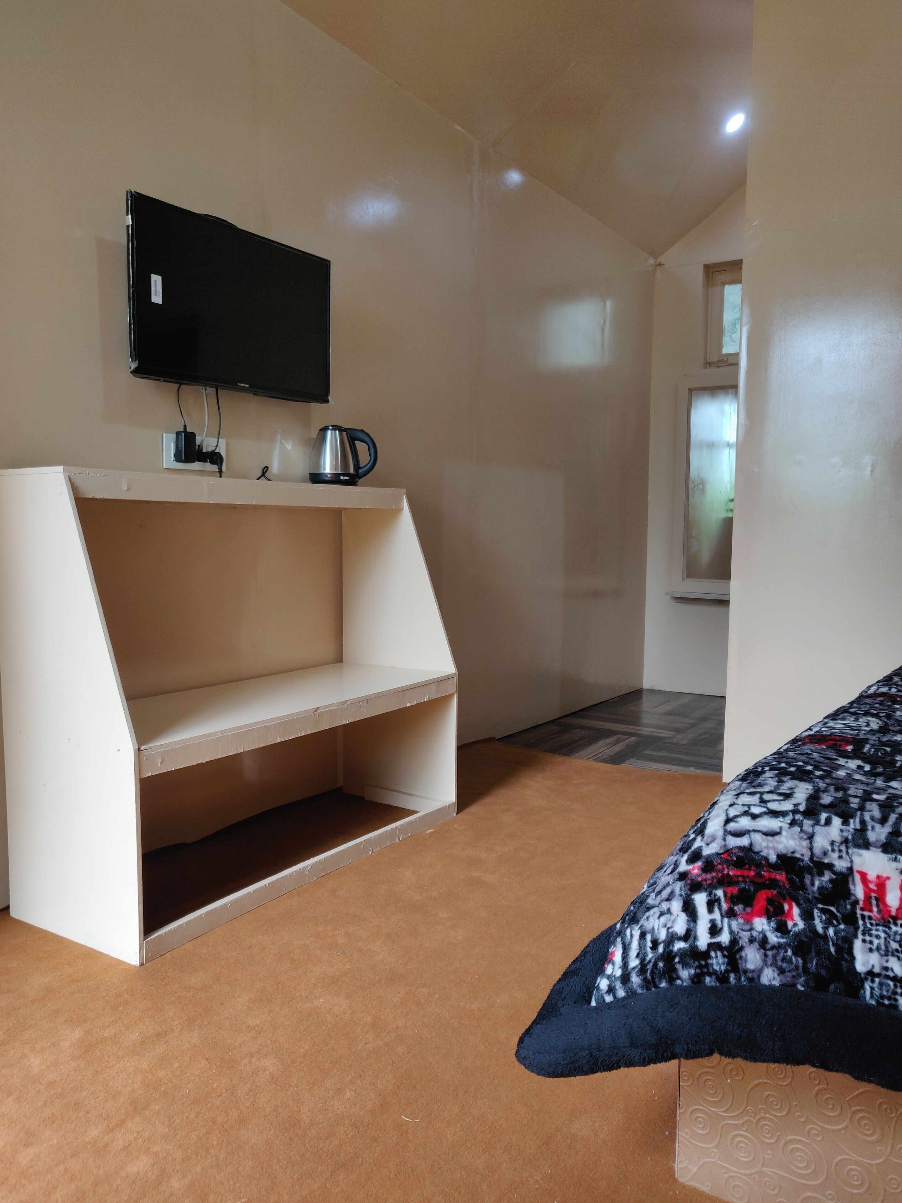 Ein Zimmer mit einer weißen Einbaubank, einem an der Wand befestigten Flachbildfernseher und einem gemusterten Zierkissen auf dem Bett.