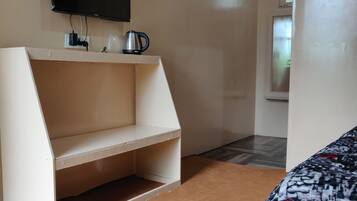 Ein Zimmer mit einer weißen Einbaubank, einem an der Wand befestigten Flachbildfernseher und einem gemusterten Zierkissen auf dem Bett.