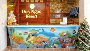 A reception desk with a marine-themed mural, a wooden sign reading "Duy Ngoc Resort", and a Christmas tree. - Duy Ngoc Resort Phu Quoc (Phu Quoc)