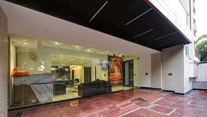 Un edifici modern amb façana de vidre, una gran estàtua de Buda i una zona de recepció amb taulell i seients.
