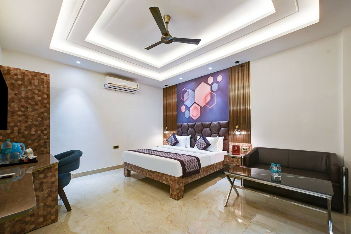 Una habitación de hotel moderna con una cama, un escritorio, un sofá y un ventilador de techo.