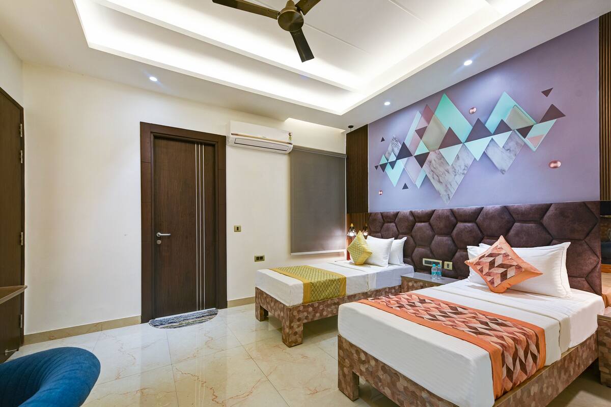Una habitación de hotel con dos camas, un ventilador de techo, un equipo de aire acondicionado y una decoración de pared.