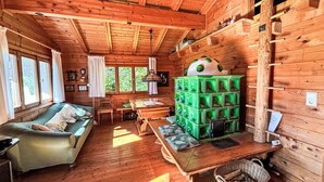 A cozy cabin interior with a wooden ceiling, a green sofa, a wooden table, and a unique green storage unit. - Stunning private villa for 5 guests with TV, patio and panoramic view (Niederöblarn)