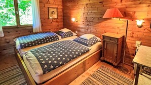 A wooden cabin room with a bed, a nightstand, a lamp, and a window with curtains. - Stunning private villa for 5 guests with TV, patio and panoramic view (Niederöblarn)