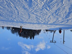 A ski resort with a clear blue sky, snow-covered slopes, and ski lifts.