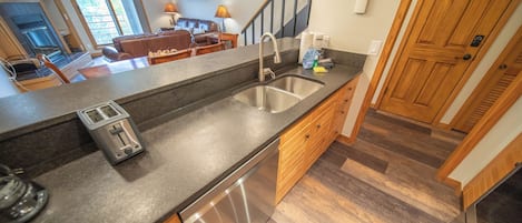 A kitchen with a built-in dishwasher, a double sink, and wooden cabinets.