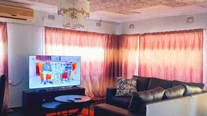 Una sala de estar con televisor, sofá, mesa de centro y candelabro.